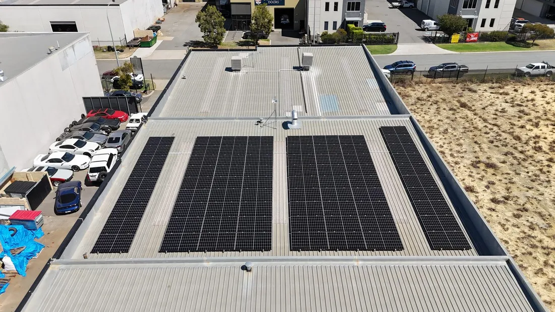 Rows of solar panels across a commercial warehouse roof, seen from above