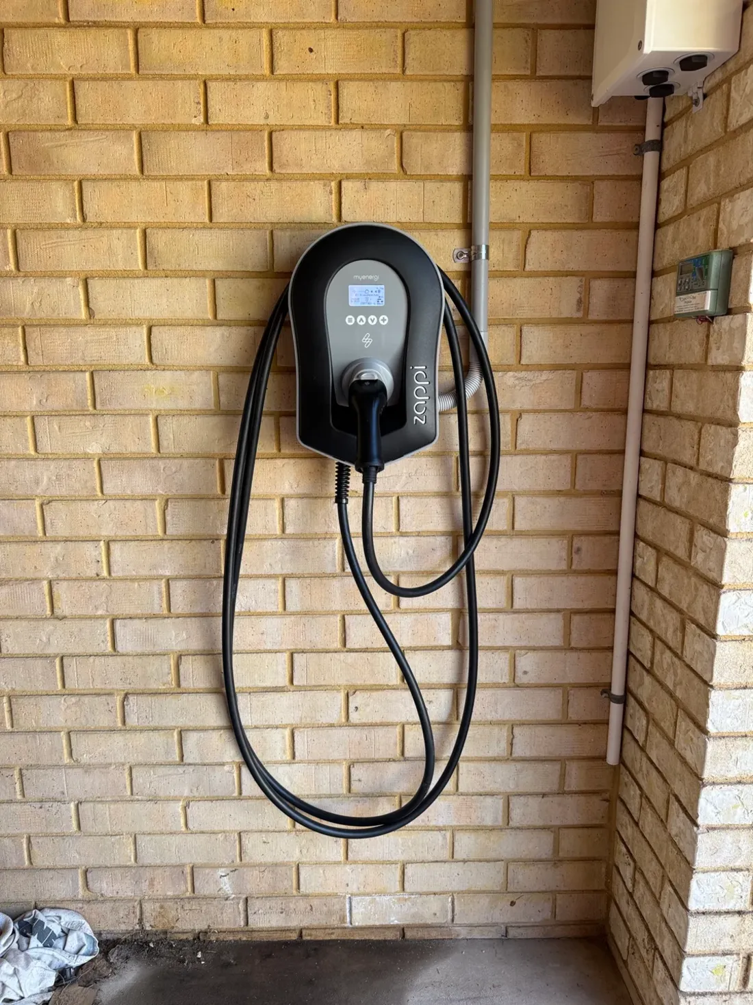 A wall mounted EV charger with a tethered cable, installed by SolArk Electrical at a Port Kennedy home