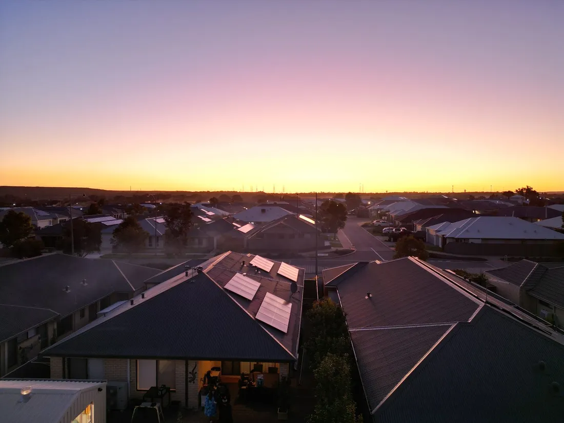 Suburban rooftops at sunset, some carrying solar panels