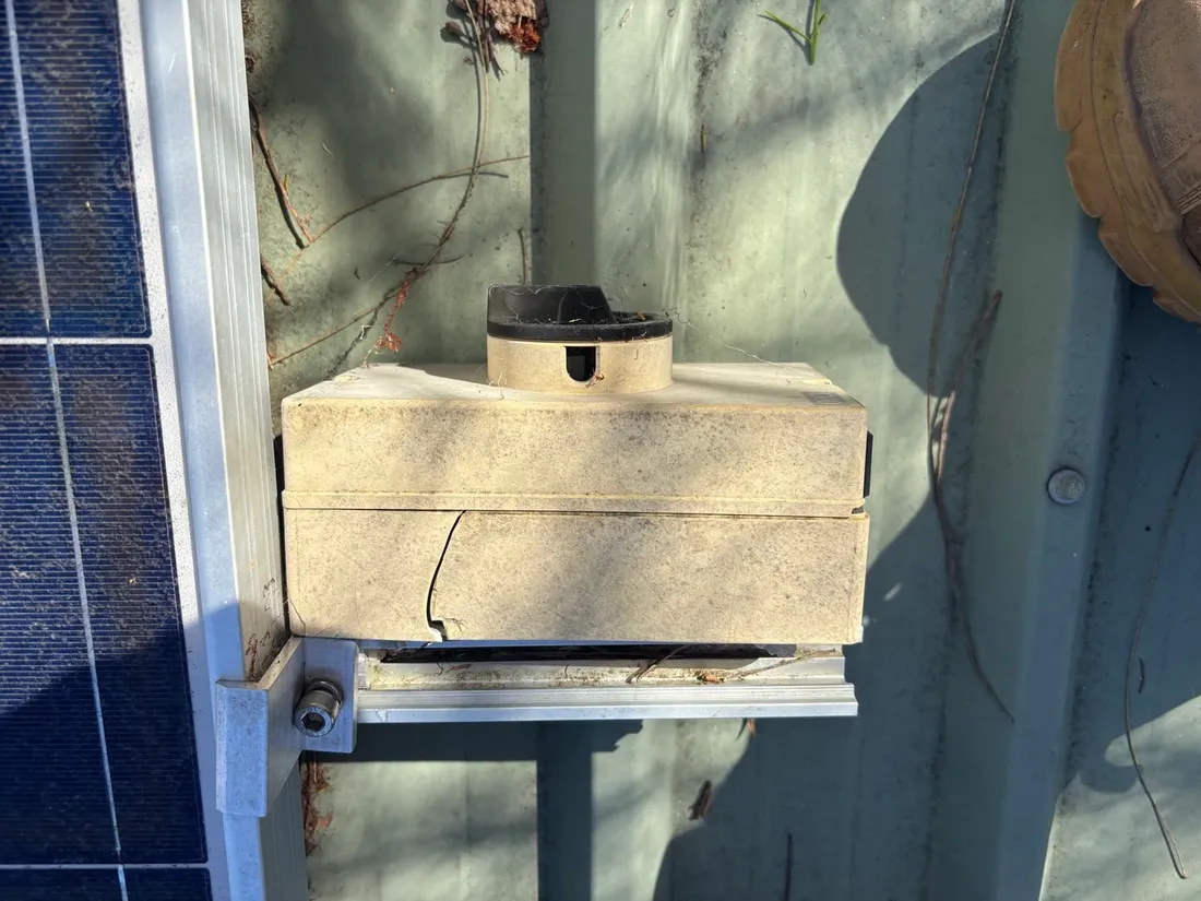 A rooftop solar DC isolator with a cracked, UV damaged enclosure, beside a solar panel at a Wanneroo home