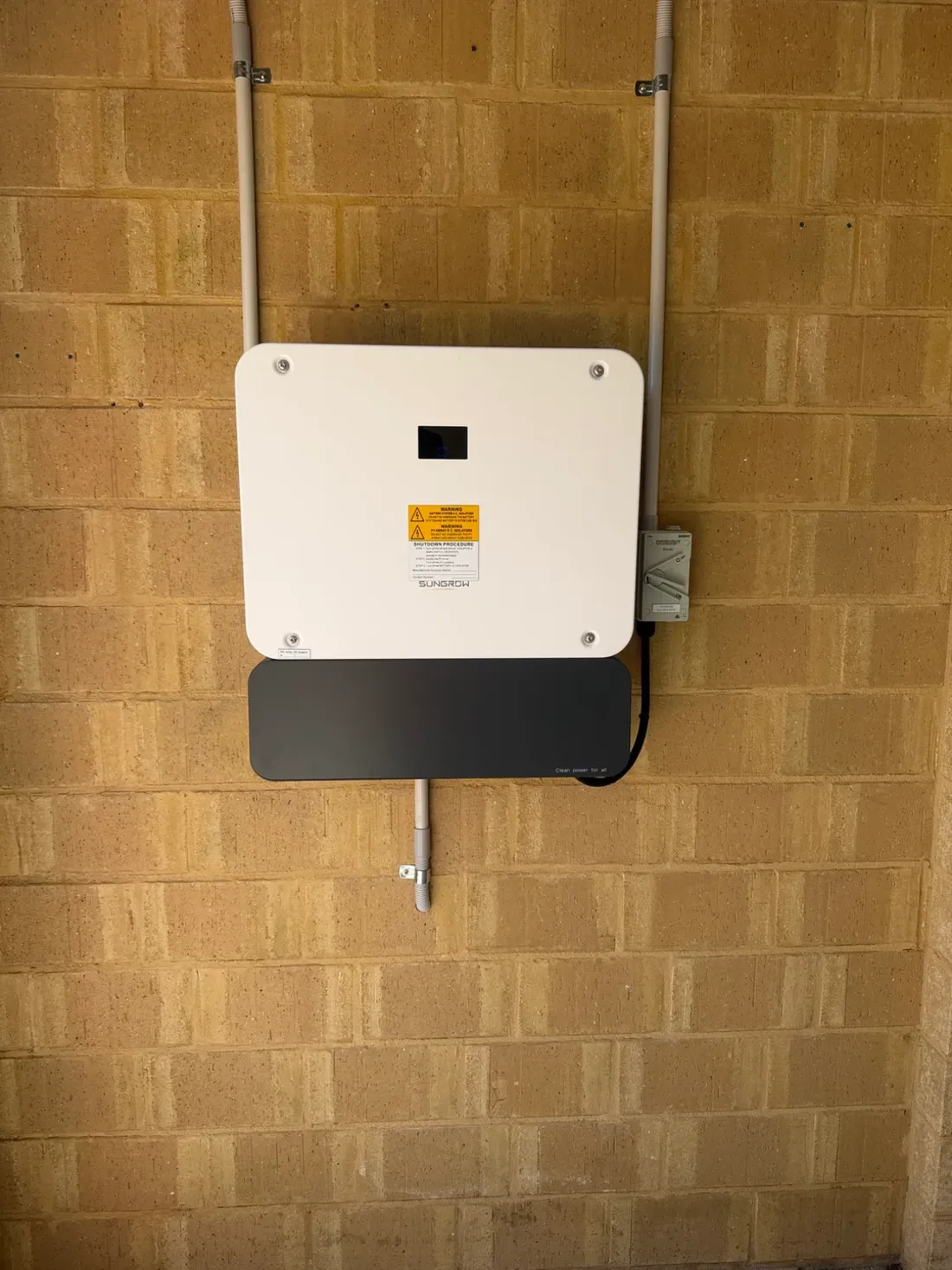 A solar inverter mounted on a brick wall at a Balcatta home, installed by SolArk Electrical