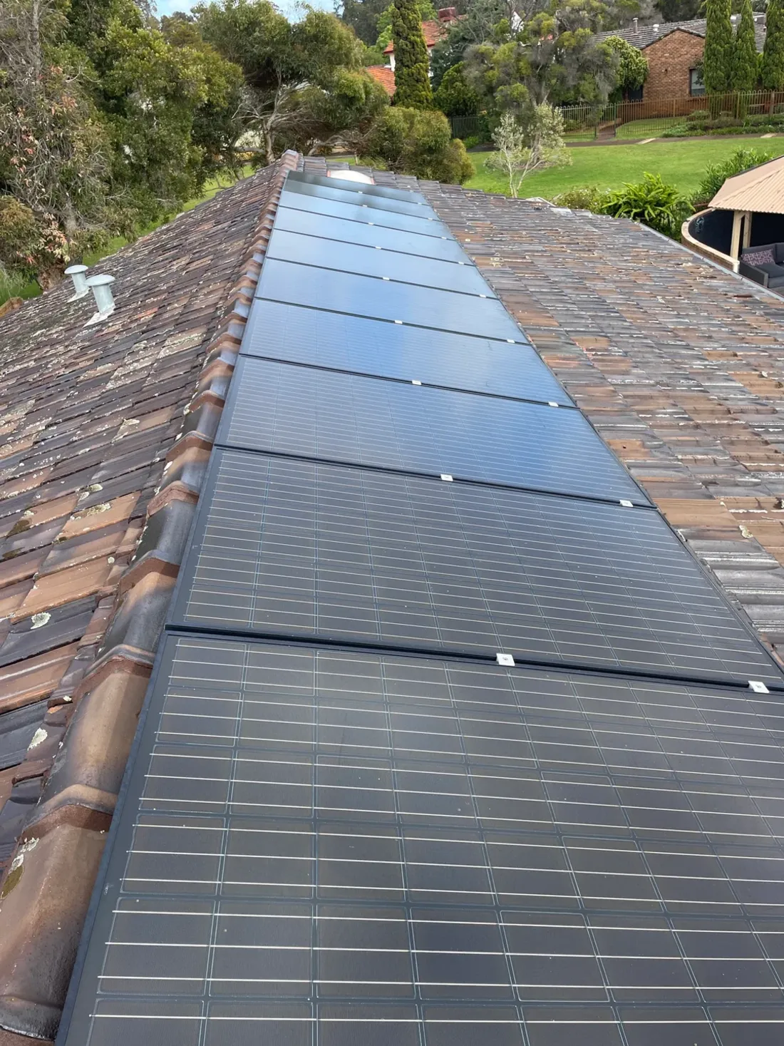 A long row of solar panels along the ridge of a tiled roof in Thornlie, installed by SolArk Electrical