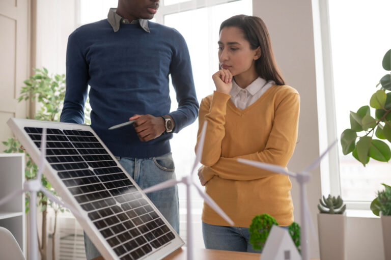A man and woman discussing in an office while pointing to a solar panel.