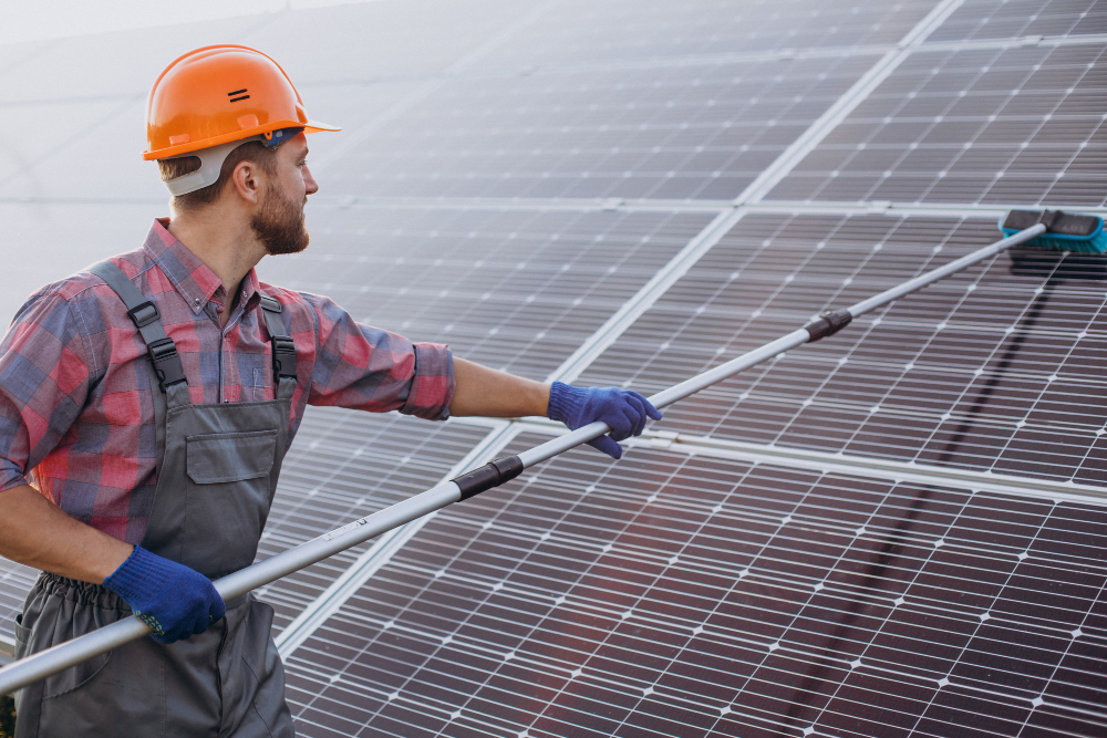 A male technician cleaning solar panels with a brush.