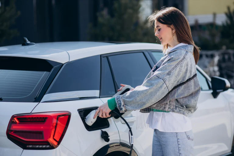 A young woman charging an electric vehicle with a charging pistol.