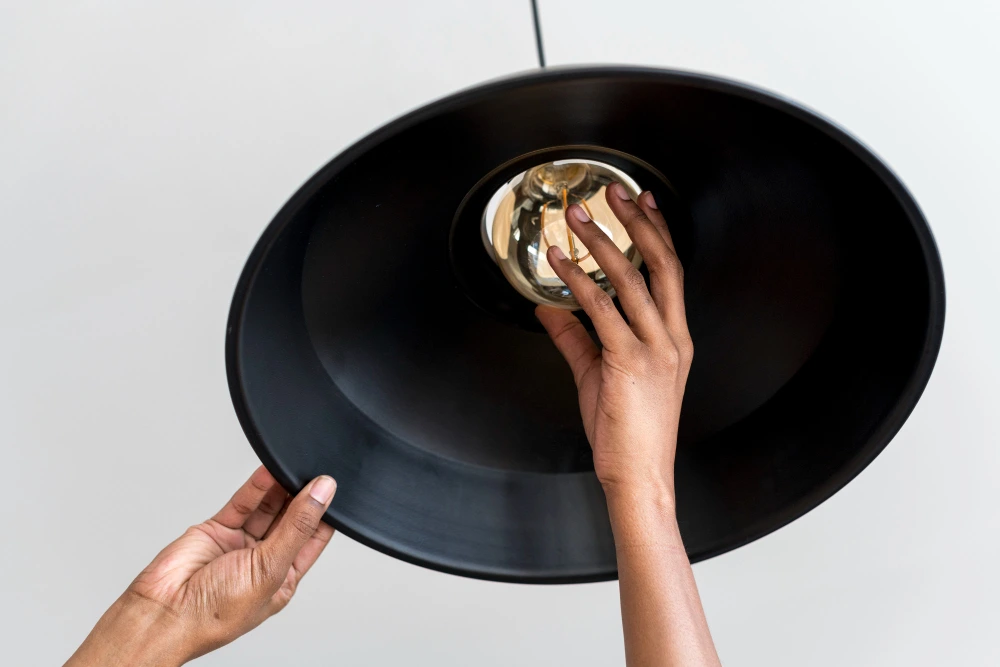 A close-up of hands changing a light bulb.