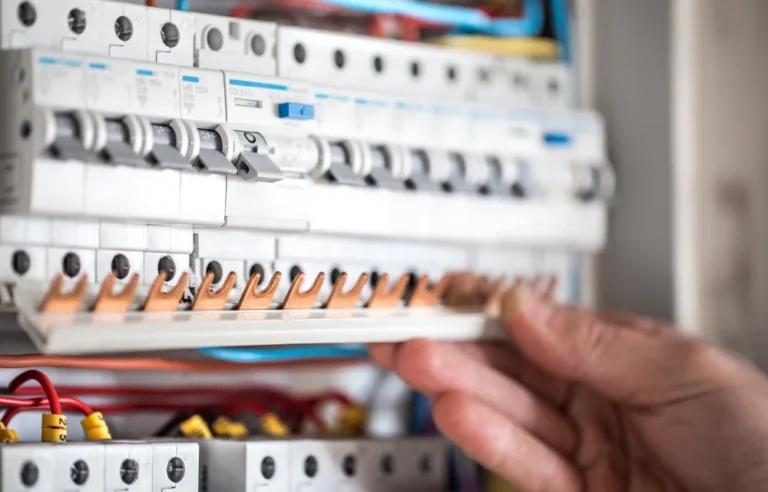 A close-up of an electrician's hand inspecting a switchboard.