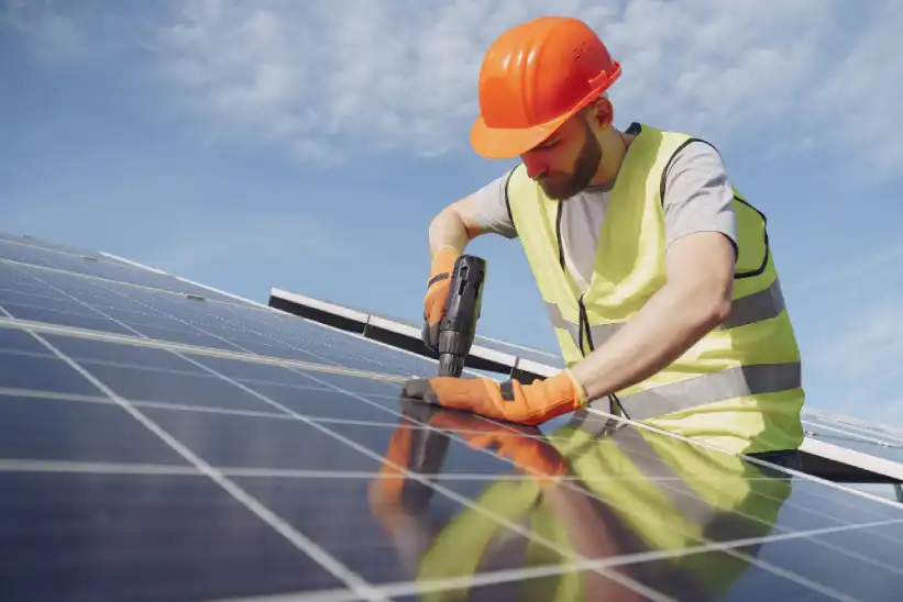 A close-up of a male professional installing solar panels on a roof.