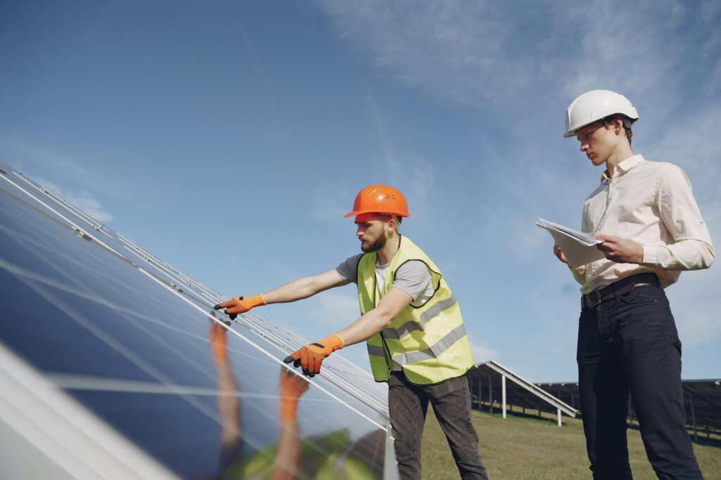 Technicians inspecting solar panels at a solar farm for a solar company in Perth under a clear blue sky.