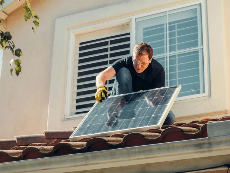 A man performing solar panel installation in Perth on a residential roof.