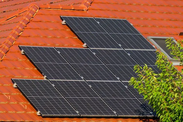 A close-up of a red tiled roof with solar panels.
