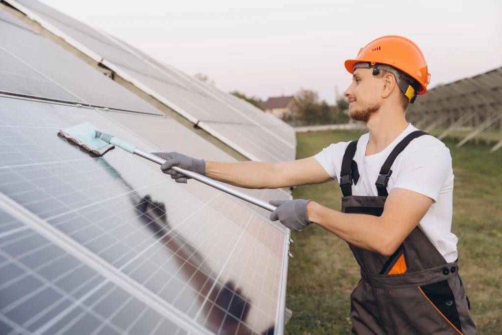 A male technician cleaning solar panels with a brush during a solar installation in Perth.